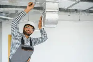 Technician Repairing Leaking HVAC System In Wichita Home